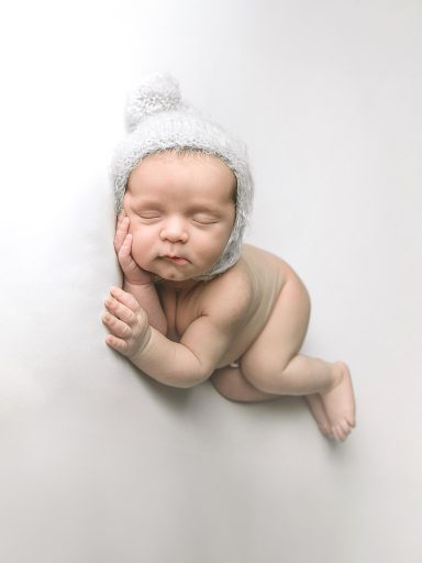 RECIEN NACIDO CORNELLA DE LLOBREGAT Bebé dormido con gorro blanco sobre fondo blanco.