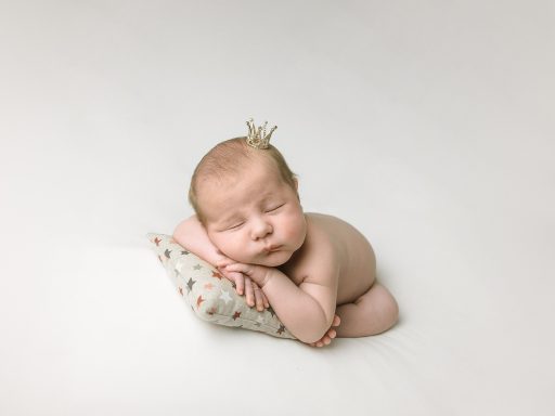 RECIENNACIDO EN ASTURIAS Bebé dormido en posición fetal sobre un cojín, con una diadema en la cabeza.